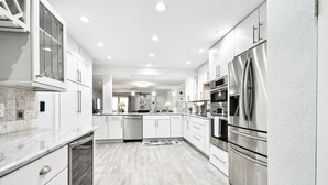 Una cocina moderna con armarios blancos, electrodomésticos de acero inoxidable y encimera de mármol.