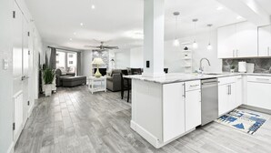 Una cocina moderna con armarios blancos, encimera de mármol y lavavajillas integrado.