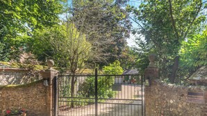 A gated entrance to a property with a stone wall and a metal gate.