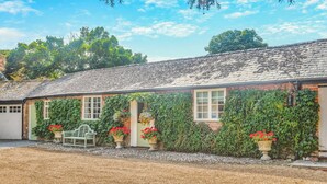 A traditional brick building with a sloped roof, a gravel driveway, and a bench.