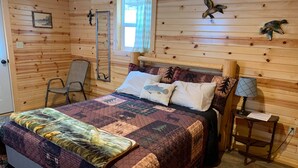 A wooden cabin room with a bed, a chair, a nightstand, and a window. - Cozy queen bed cabin with WiFi, fitness room in enchanting Aladdin (Aladdin)