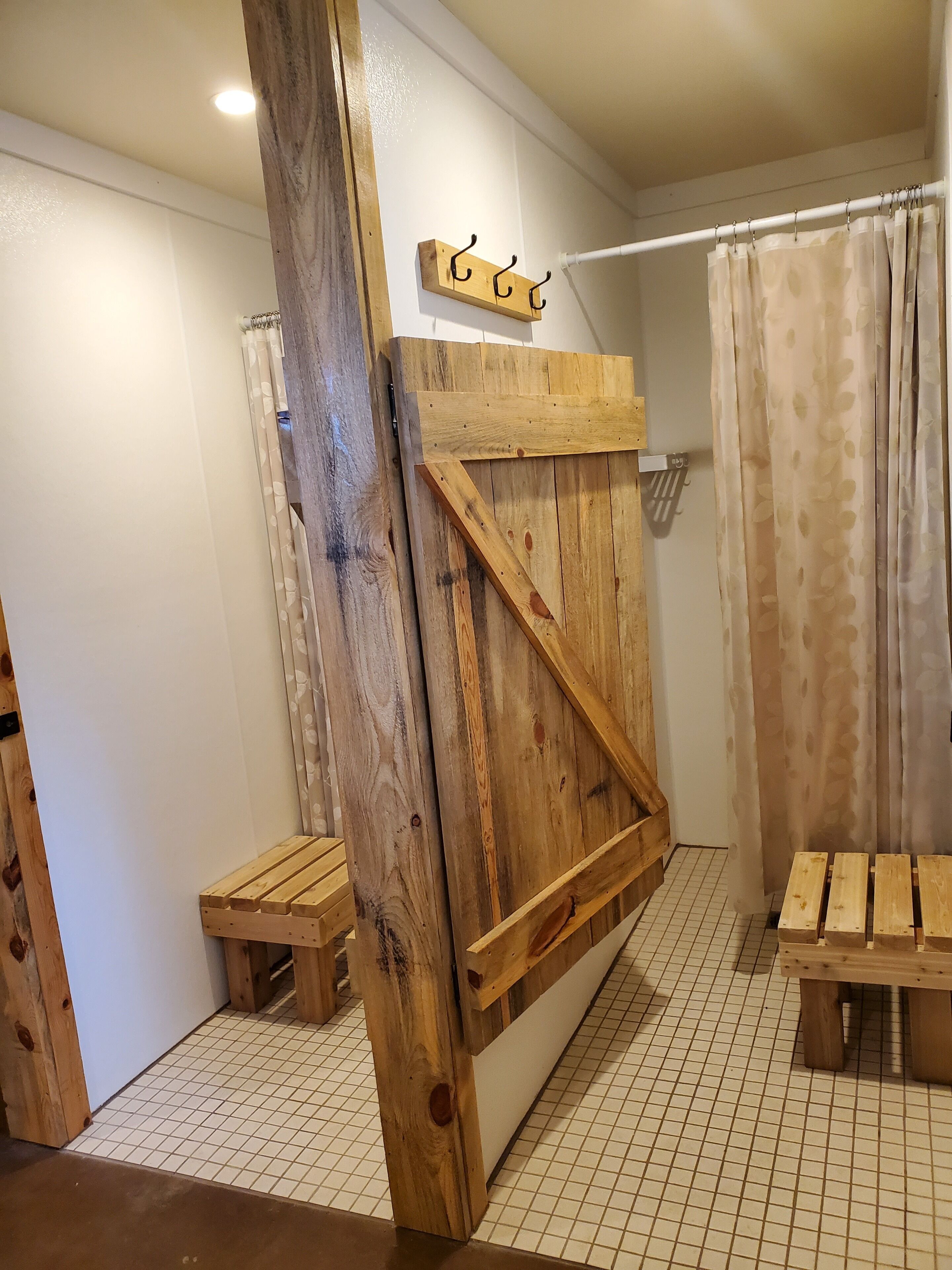 Un espace douche avec une structure en bois, comprenant un banc en bois, un porte-serviettes et un rideau.