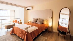 Une chambre moderne avec un grand lit, des tables de chevet, un miroir et un balcon décoré dans les tons orange.