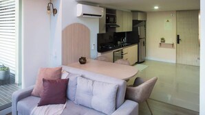 Un salon moderne avec un canapé, une table à manger et un coin cuisine à l’arrière-plan.