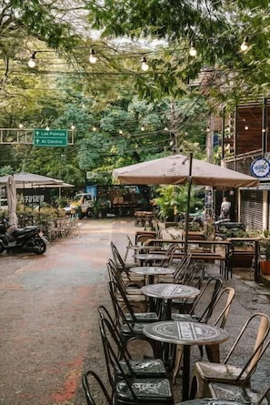 An outdoor cafe area with tables and chairs, surrounded by greenery and trees. - Private Terrace Duplex in El Poblado (Medellin)