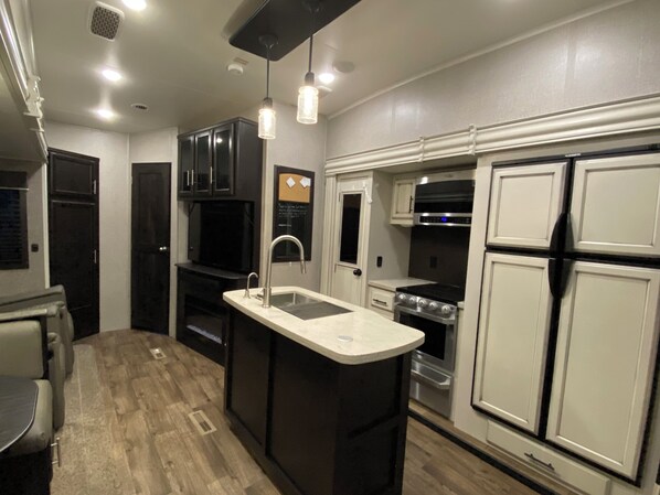 A compact kitchen with a central island, built-in appliances, and pendant lighting.