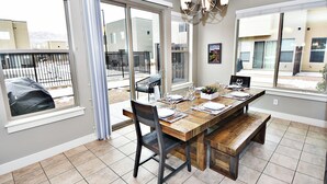 A dining area with a wooden table set for four, large windows, and a view of the outside. - Entrada at Moab 429 (Moab)