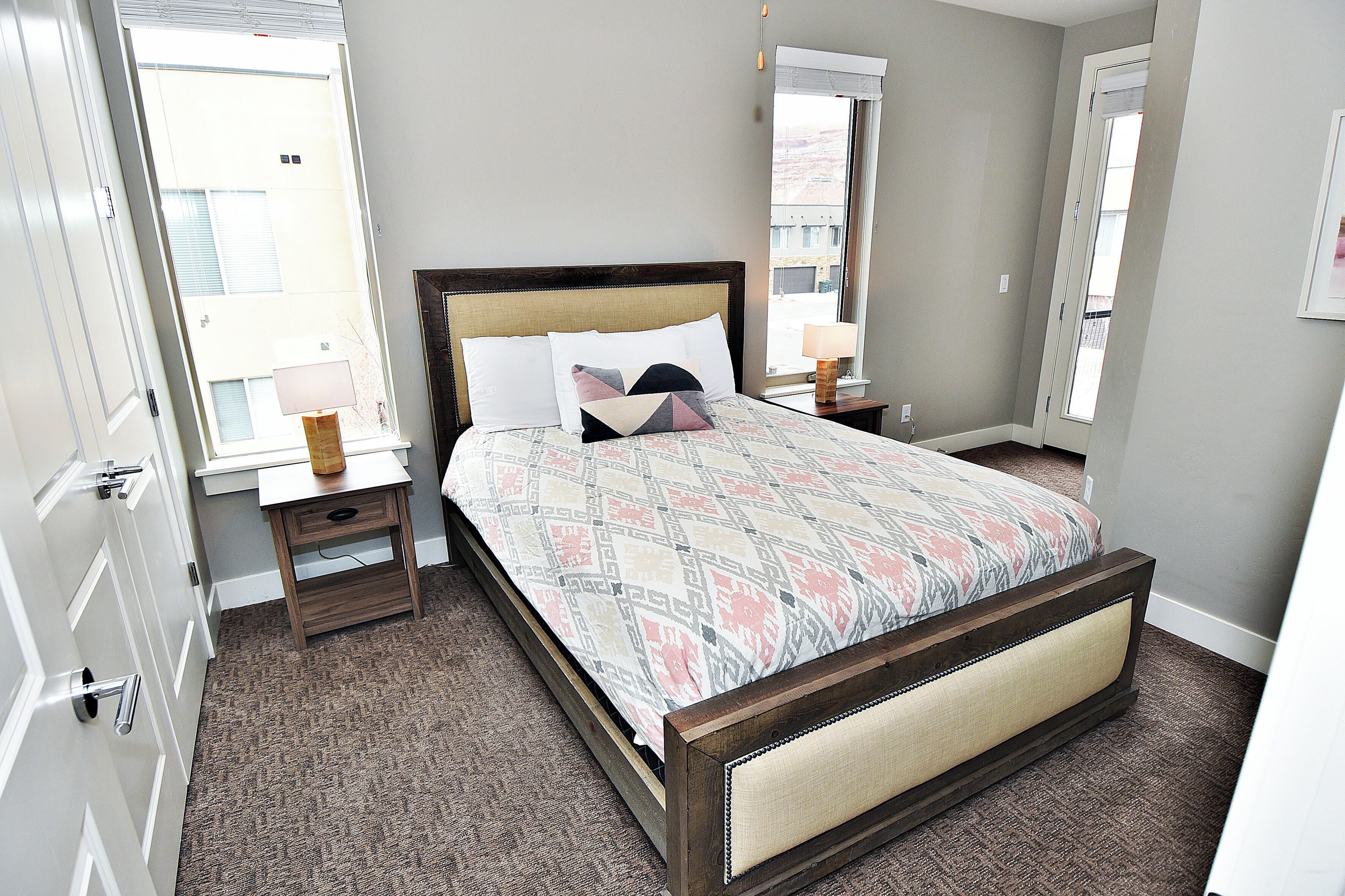 A bedroom with a bed, bedside tables, and a window.