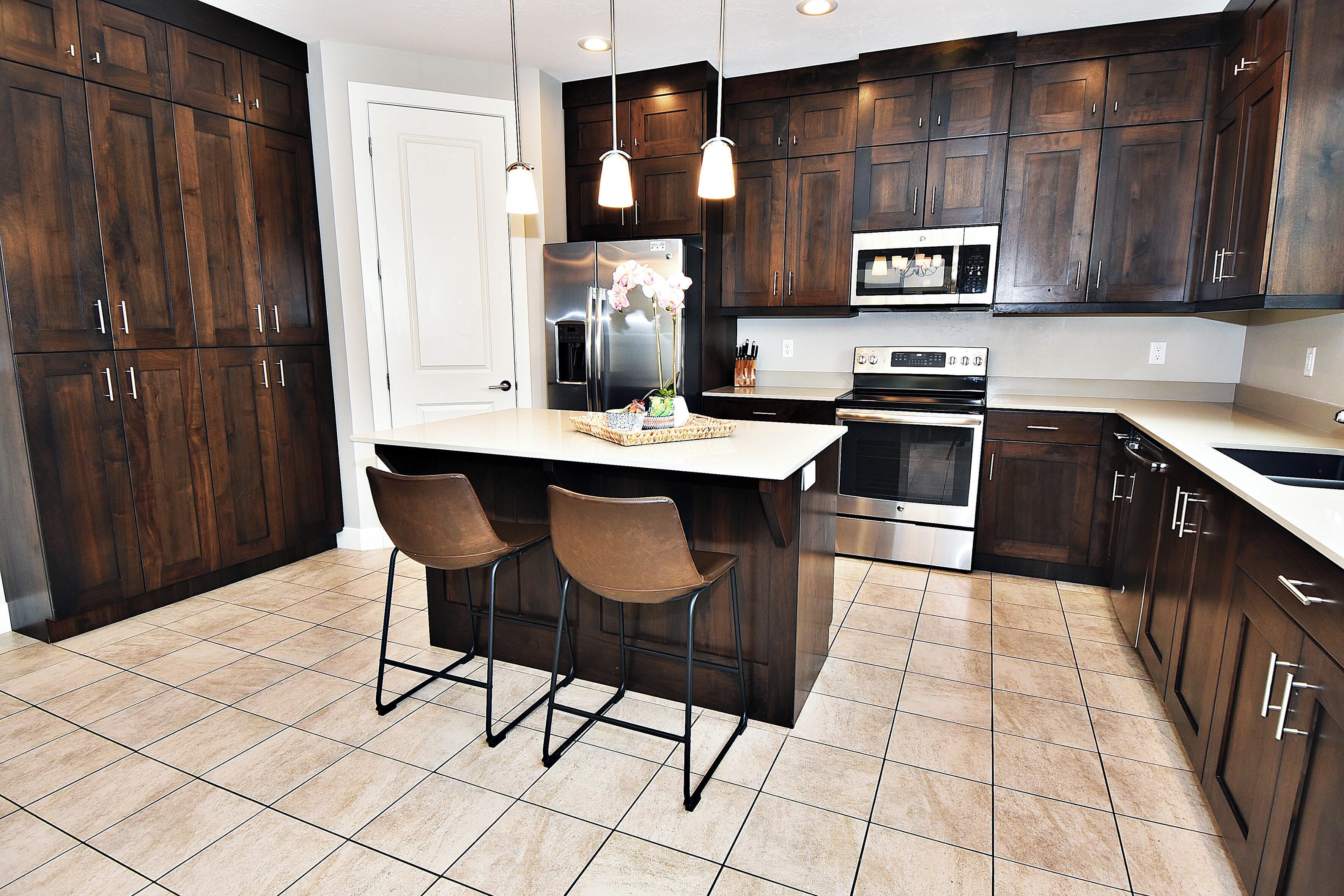 A modern kitchen with dark wood cabinets, stainless steel appliances, and a central island with bar stools.