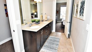 A modern bathroom with a double sink vanity, dark wood cabinets, a large mirror, and a patterned rug. - Entrada at Moab 429 (Moab)