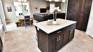 A modern kitchen with dark wood cabinets, a large island, and a dining area with a leather couch. - Entrada at Moab 429 (Moab)