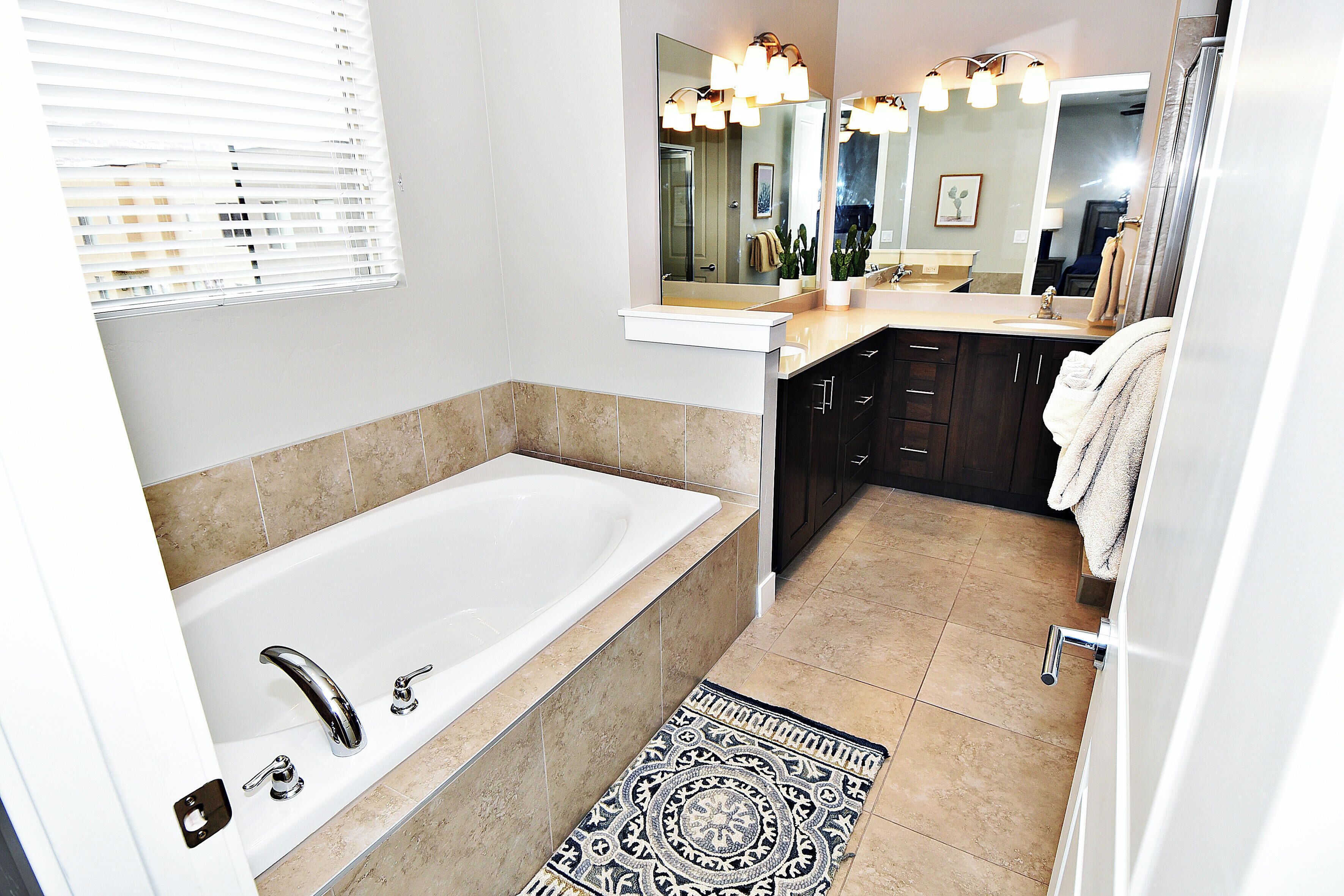 A modern bathroom with a bathtub, a vanity with a mirror, and a shower area.