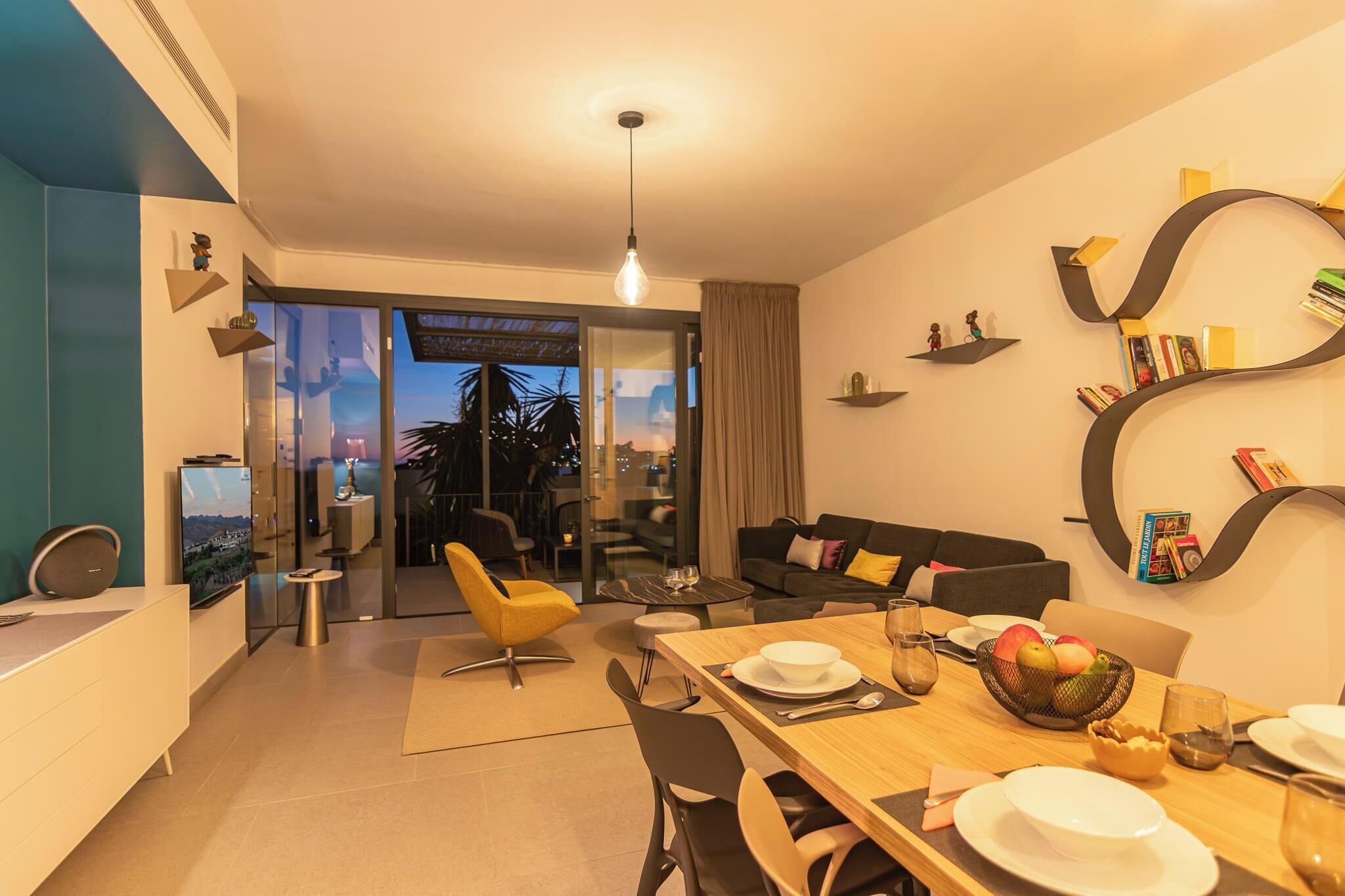 Una sala moderna con comedor, un sofá, un televisor y vistas a la ciudad.