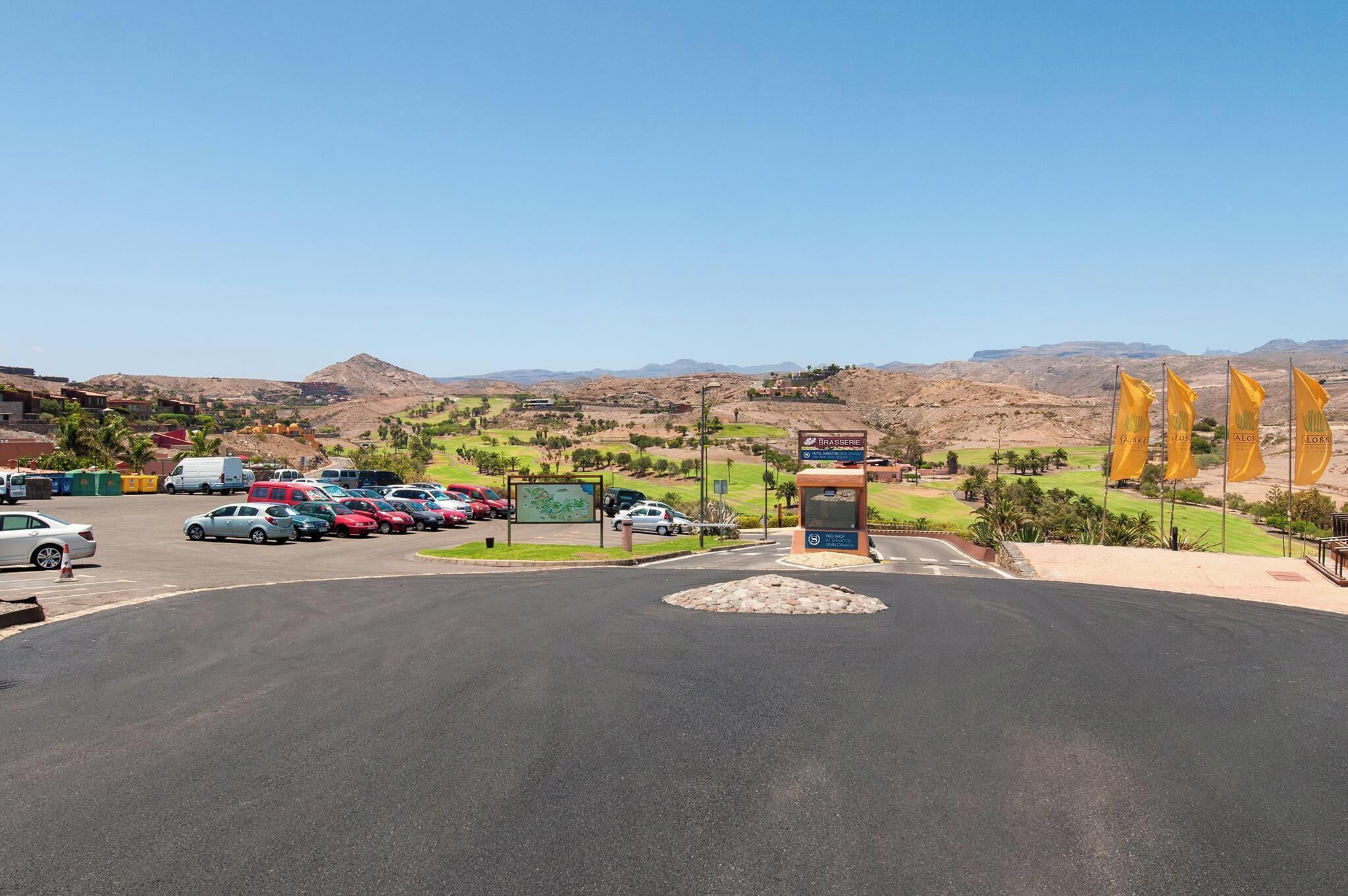 A parking lot with several cars, a small kiosk, and a sign for Brasserie.