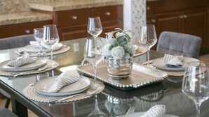 Une table à manger dressée avec des assiettes, des couverts et des verres à vin, agrémentée d’un centre de table décoratif.