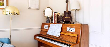 A piano with sheet music, a mirror, and a guitar on a wooden stand.