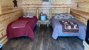 Une chambre confortable de style cabane, avec deux lits, des murs en bois, un seau en métal et une décoration en forme d’étoile.
