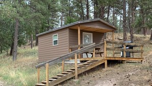 Une petite cabane avec un escalier en bois menant à une véranda.