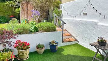 Un jardin avec des plantes en pot, un mur blanc et un escalier.