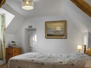 A bedroom with a bed, a dresser, a lamp, a painting, and a ceiling light fixture. - 3 bedroom accommodation in Walgrave (Walgrave)