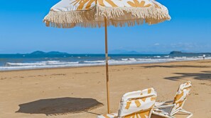 A beach scene with a beach umbrella and two beach chairs.