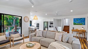 Una sala de estar moderna con sofá, sillas, una mesa de centro y una zona de comedor.