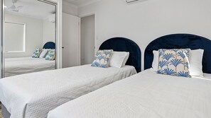 A hotel room with two beds, white bedding, and matching headboards.