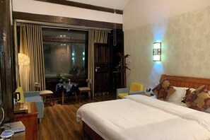 A hotel room with a large bed, a desk, a chair, and a small table. - Lijiang Blue Stone Inn (Lijiang)