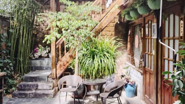 Ein Innenhof mit einer Steintreppe, Bambuspflanzen und einem Tisch mit Stühlen.