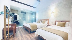 Ein Hotelzimmer mit zwei Betten, einem Schreibtisch und einer Glastrennwand.