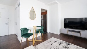 A modern living room with a dining area, a large flat-screen TV, and a kitchen visible through an open door. - Beautiful Studio Downtown NYC (New York)