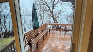 A wooden deck with a bench and a welcome mat.