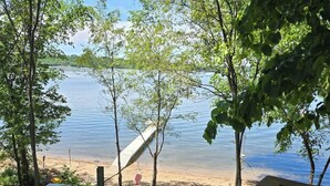 A lakeside view with a wooden bench, a picnic table, and a swing set.