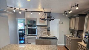 A modern kitchen with granite countertops, stainless steel appliances, and a central island with bar stools.