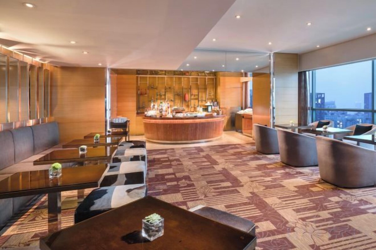 Eine Hotlellobby mit Barbereich, Sitzgelegenheiten und einem gemusterten Teppich.