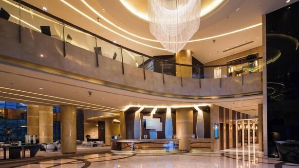 Un hall d’entrée spacieux avec un plafond haut, un lustre central et un comptoir d’accueil.