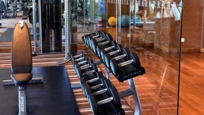 Une salle de sport avec des haltères de la marque « MATRIX » sur un porte-haltères, un banc et des ballons d’exercice en arrière-plan.