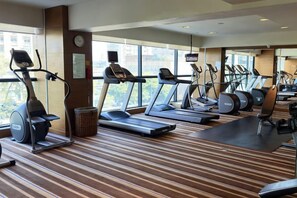 Ein Fitnessstudio mit Laufbändern, Crosstrainern und Trainingsmatten.