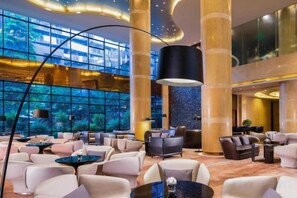 Eine geräumige Lobby mit hohen Decken, großen Fenstern und moderner Möblierung.
