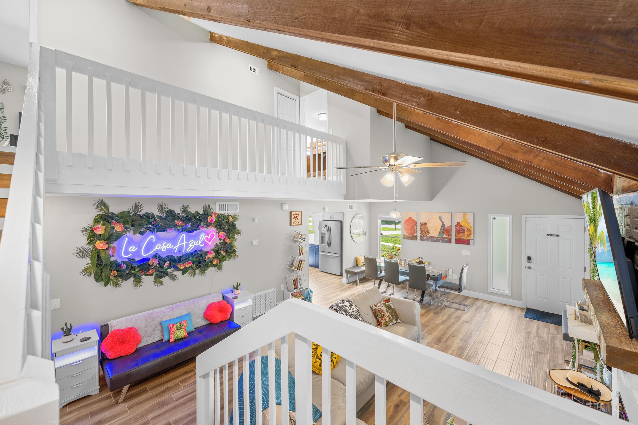 Un loft spacieux avec de hauts plafonds, des poutres apparentes, un balcon, un néon, une cuisine et un coin repas.