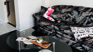 Una sala de estar moderna con un sofá negro, una mesa de centro de vidrio y un diseño minimalista.