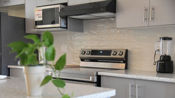 Una cocina moderna con electrodomésticos de acero inoxidable, microondas, horno y cafetera.