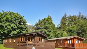 Two wooden cabins with a fenced yard and a satellite dish. - 3 bedroom accommodation in Rowardennan (Rowardennan)