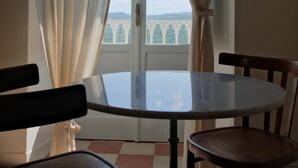 A room with a round table and two chairs, a window with curtains, and a view of a bridge. - La Dimora di Pindaro (Colledimacine)