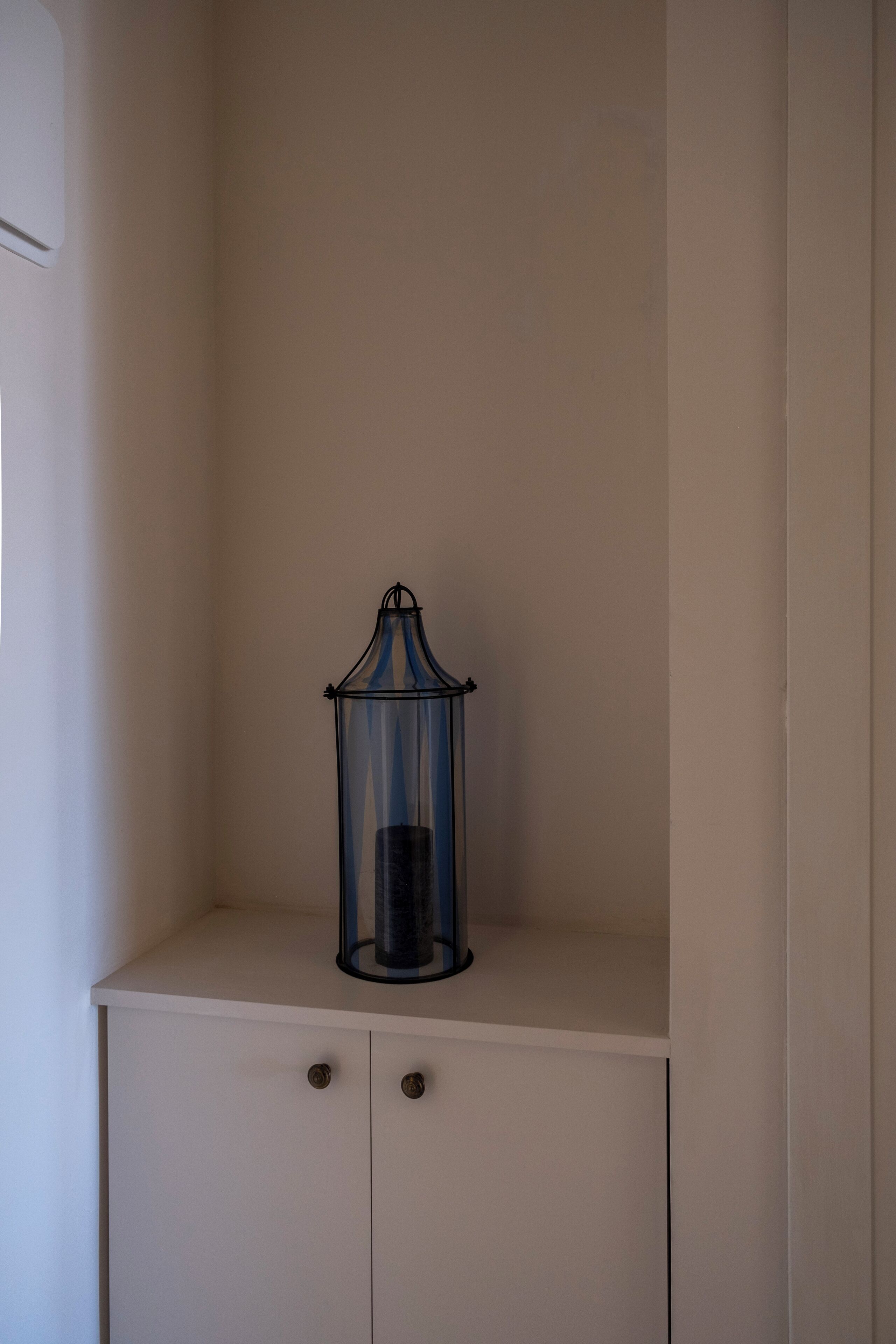 A white cabinet with two drawers and a glass lantern on top.