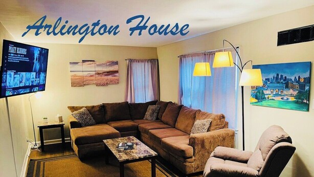A living room with a sectional sofa, a coffee table, a chair, and a TV mounted on the wall. - Arlington House - 5 min to Arrowhead / FIFA (Independence)