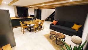 A modern living space with a dining area, a sofa, and a staircase. - Gîte des trois châteaux (Husseren-les-Châteaux)