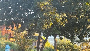 Een achtertuin met Adirondack-stoelen, een vuurkuil en een blauwe parasol.
