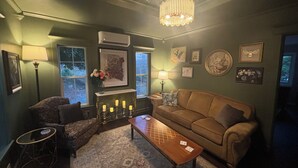 Ein gemütliches Wohnzimmer mit einer braunen Couch, einem gemusterten Teppich und einer Chandelüster.