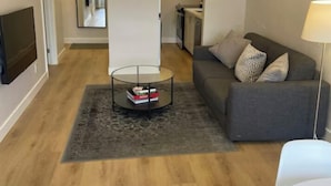 Una sala de estar moderna con un sofá gris, una mesa de centro y un televisor montado en la pared.
